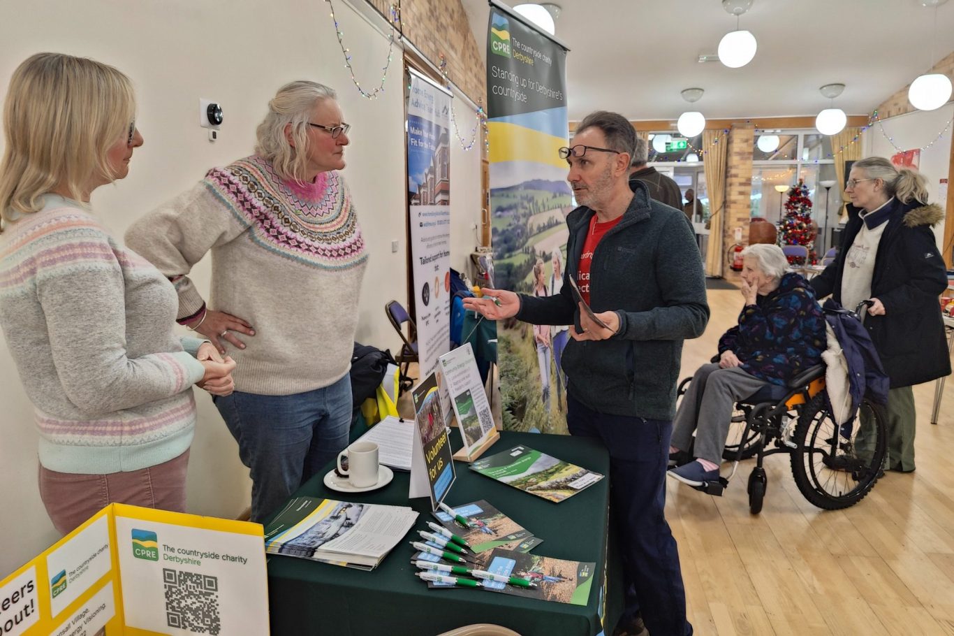 A conversation at a community event, with a table displaying informational materials.