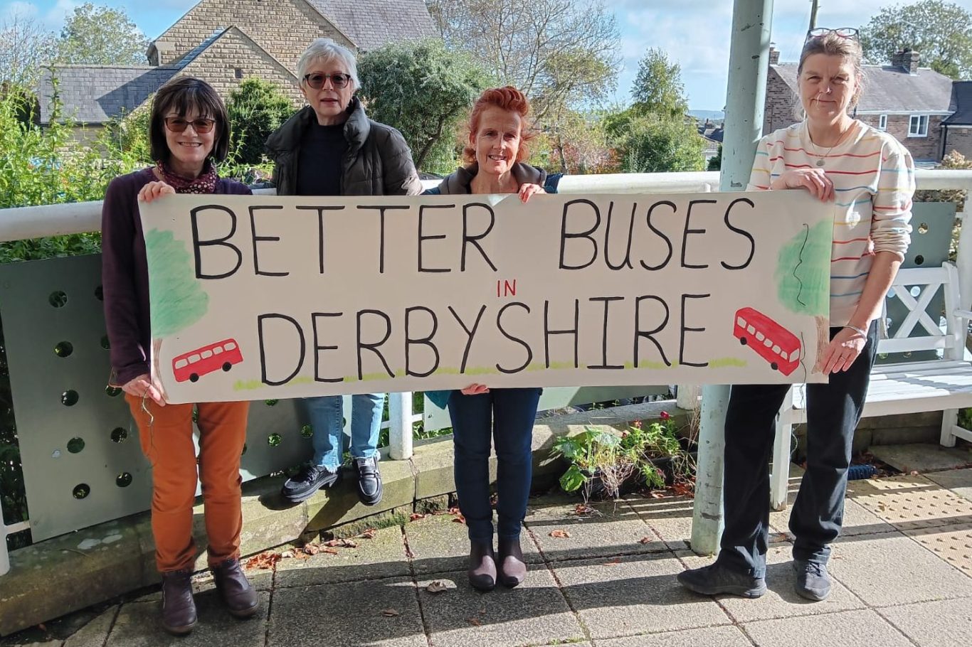 Four people holding a large sign that reads "Better Buses Derbyshire."